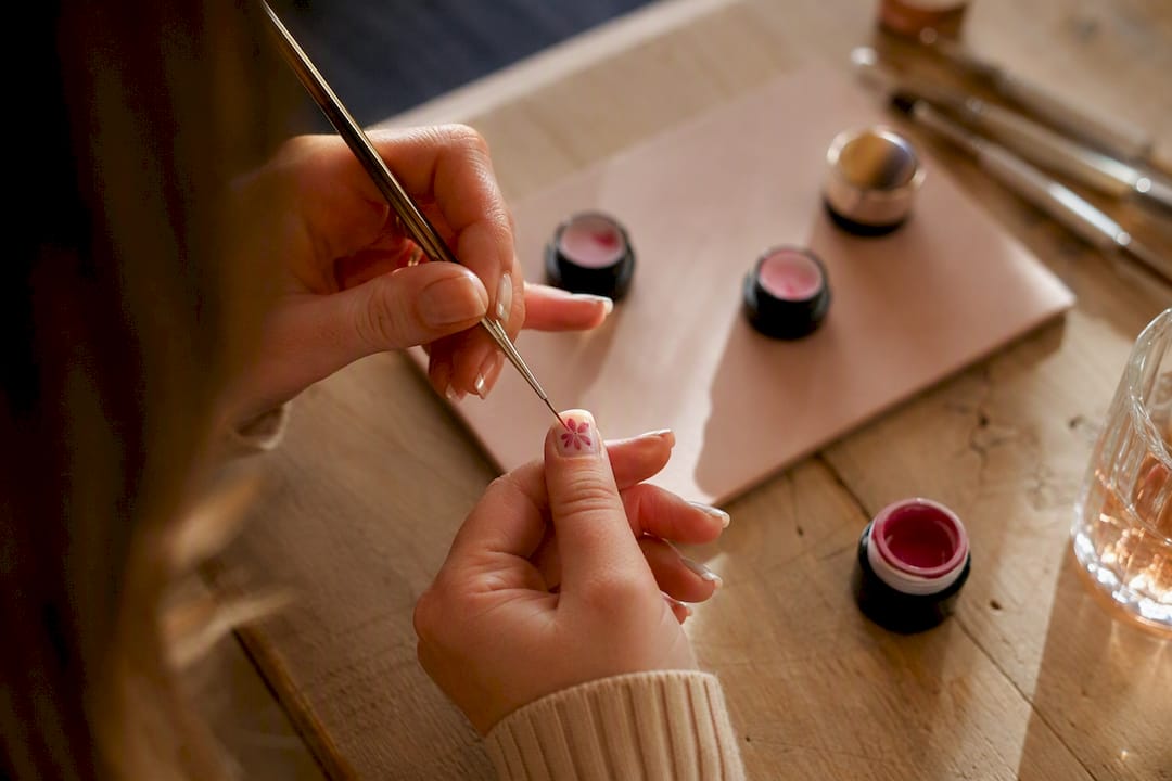 Close-up van een hand die bloemrijke nagelkunst schildert